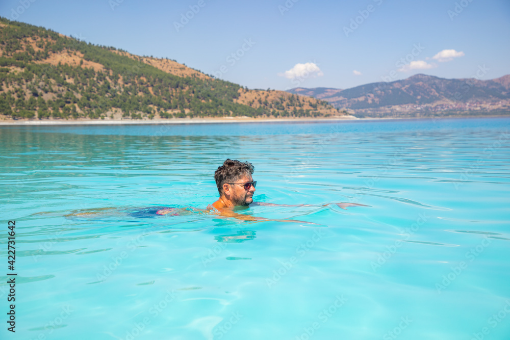 Man is swimming in turquoise crater lake Salda Golu, Turkey