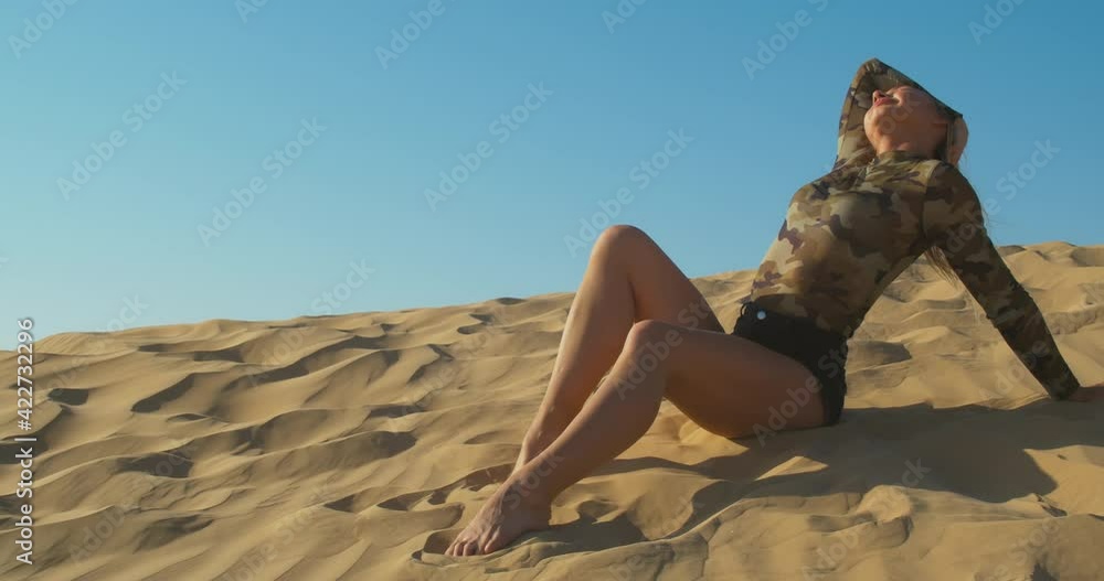 Woman in black shorts is sitting on a side of a sand dune, posing, desert, 4k Woman in black shorts is sitting on a side of a sand dune, posing, desert, 4k