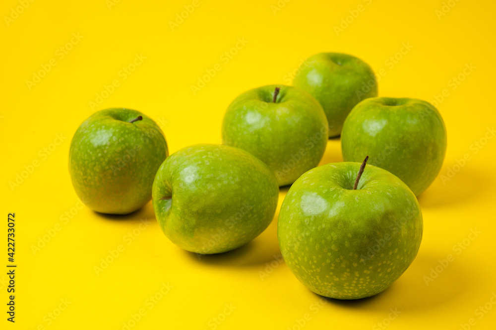 Large green apples, ripe and juicy. Photographed against a uniform yellow background. Large green apples, ripe and juicy. Photographed against a uniform yellow background.