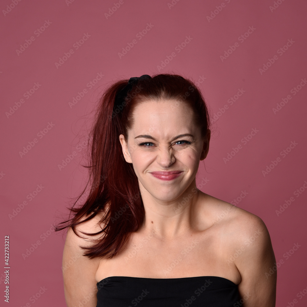 Fototapeta premium close up portrait of red haired women with different facial expressions on a pink studio background.