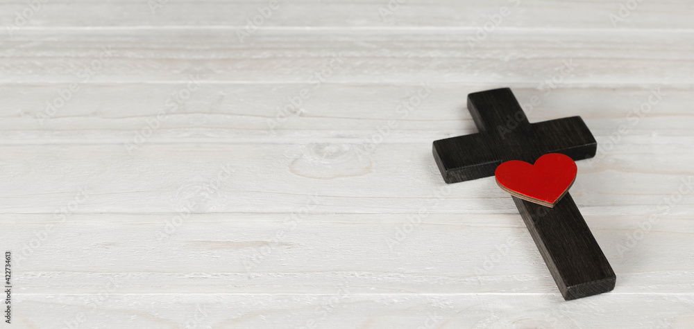 Wooden cross of Jesus. Red heart love. On a wooden white background. Death symbol. Religious christian