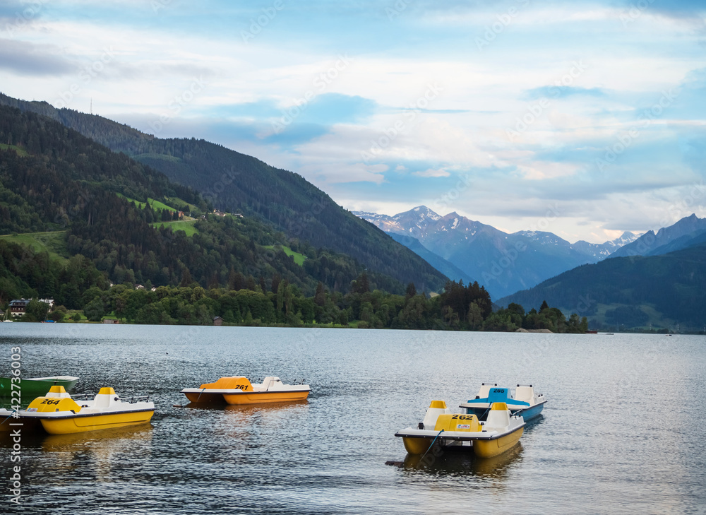 Colorful pedal boats overlooking the alps mountains in the town of zell am see in austria on a camping.