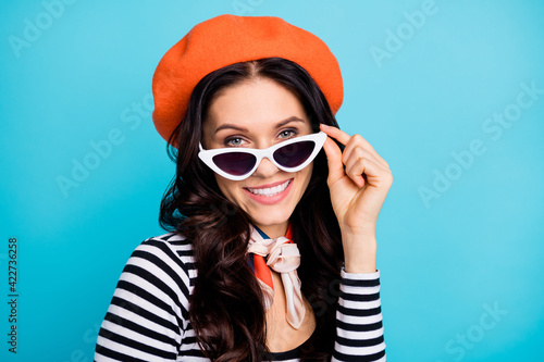 Photo of young attractive cheerful woman happy positive smile hand touch sunglass isolated over blue color background