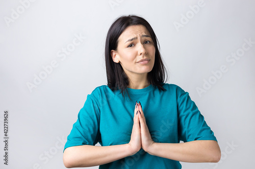 Quadro em tela Pretty girl with helpless expression, asks for help, keeps palms pressed together