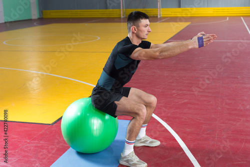 Athletic guy in sportswear and fitness tracker doing exercises in gym.