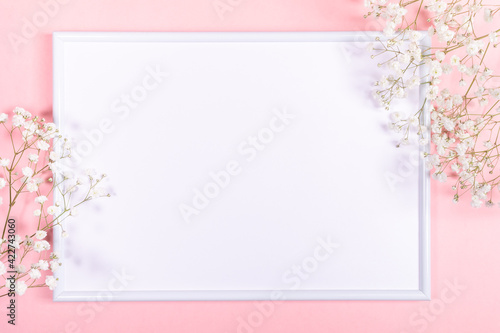 Frame with white copy space and gentle white gypsophila flowers on pastel pink. Spring festive background. © SeNata