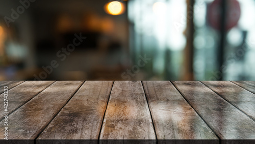 Empty wooden table top with lights bokeh on blur restaurant background.