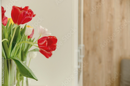 Beautiful spring multicolored tulips in a light interior next to white wardrobe. High quality photo