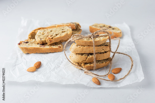 А stack of cookies tied with eco rope and blurred cookies on background. Italian biscotti cookies on baking paper. Classic recipe