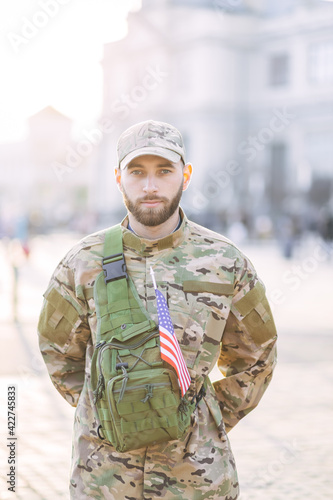 officer in military uniform standing near the station. Young proud male soldier standing outdoors and looking at the camera. Military service concept