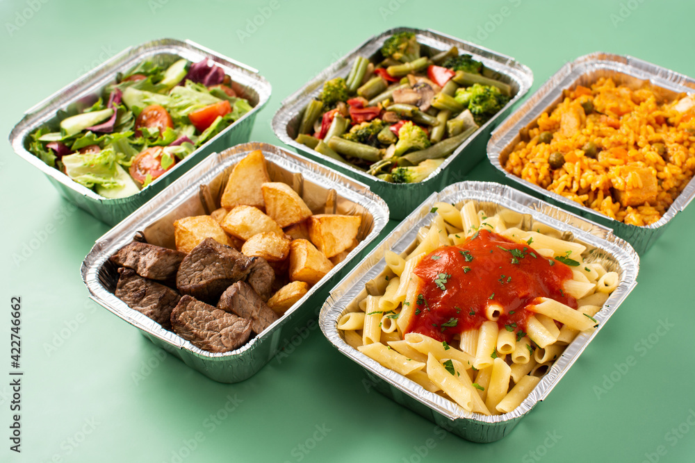 Take away healthy food in foil boxes on green background Take away healthy food in foil boxes on green background