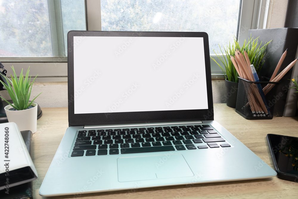 Laptop computer with white blank screen on desk in workspace and copy space concept
