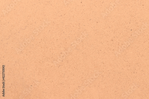 The surface of a light beige cardboard sheet. Light uniform brown texture.