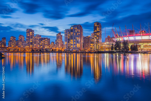 Vancouver downtown architecture and boat with water reflections at dusk