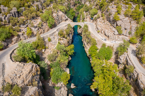 Aerial view of ancient arch bridge Oluk over the Koprucay river gorge in Koprulu national Park in Turkey. Panoramic scenic view of the canyon and blue stormy mountain river