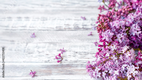 Purple lilac Spring branches of blooming lilac festive bouquet of flowers. Long web banner with copy space. Purple lilac branch on table, floral still life on gray wooden background.