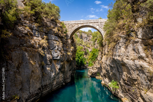 Ancient arch bridge Oluk over the Koprucay river gorge in Koprulu national Park in Turkey. Panoramic scenic view of the canyon and blue stormy mountain river photo