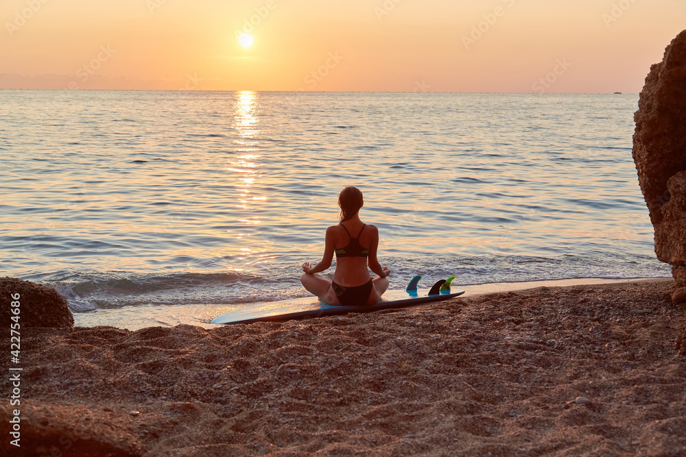 Meditation on beach at sunset. Woman practicing yoga on seashore. Relax in nature. Contemplation and meditation idea