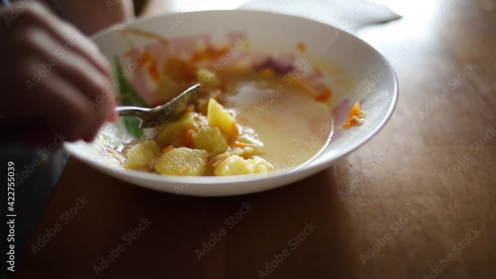 child eats with spoon from plate at home in kitchen at table. potato soup close-up. child eats with spoon from plate at home in kitchen at table. potato soup close-up.