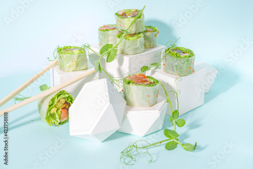 Mediterranean, nordic and keto diet concept. Sushi without rice, diet food with seafood, vegetables. Trendy asian sushi-styled Spring rolls on blue modern background