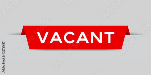 Red color inserted label with word vacant on gray background