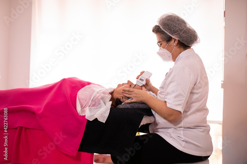 Beautician applying microcurrent to her patient in the beauty salon