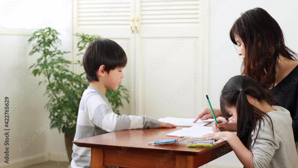 子供に勉強を教える母親とお絵かきをする女の子 子供に勉強を教える母親とお絵かきをする女の子