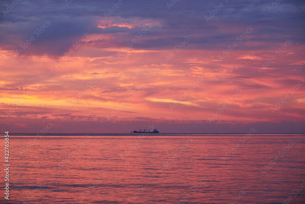 Sunset on the sea, ship standing on the horizon.