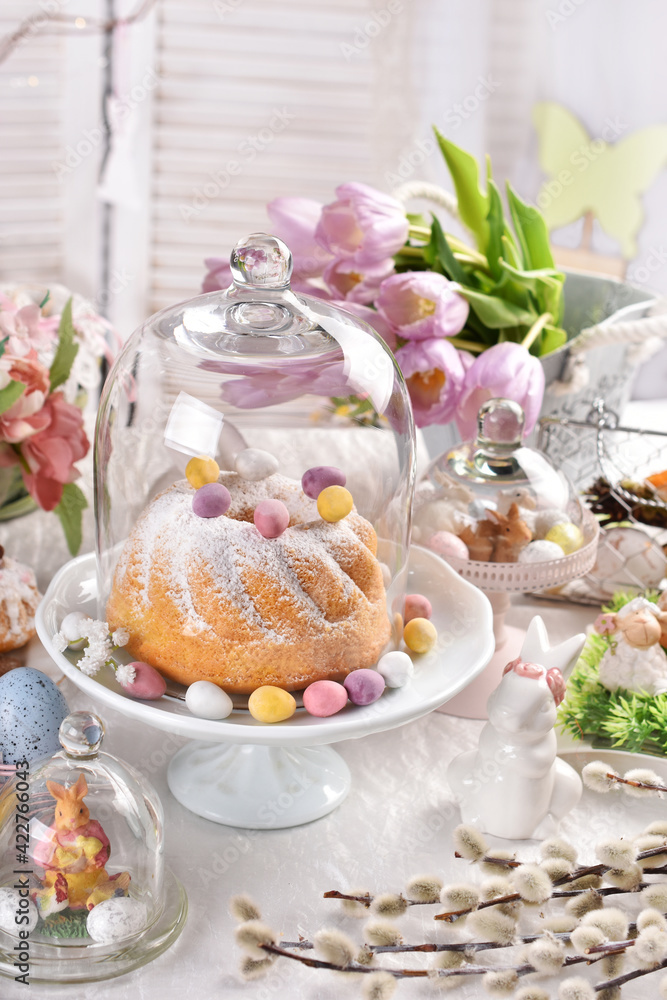 Easter table with ring cake and decors under a glass cloche Easter table with ring cake and decors under a glass cloche