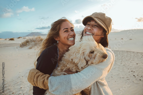 Two beautiful filipino women laughing and hugging each other and their dog