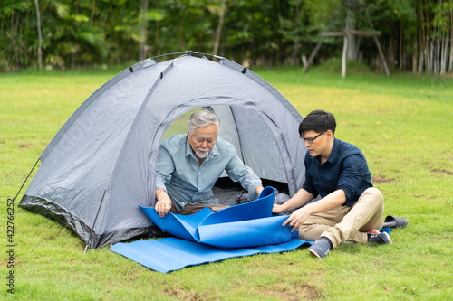 Senior Asian Father With Adult Son Enjoying Camping Holiday. senior mature father and smiling young adult Resting in the tent. Happy family time together.