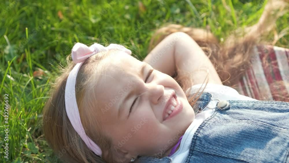 Pretty little child girl laying down on green grass in summer taking a nap. Pretty little child girl laying down on green grass in summer taking a nap.