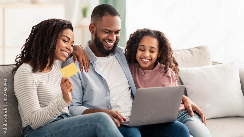 Black family using computer and credit card at home Black family using computer and credit card at home