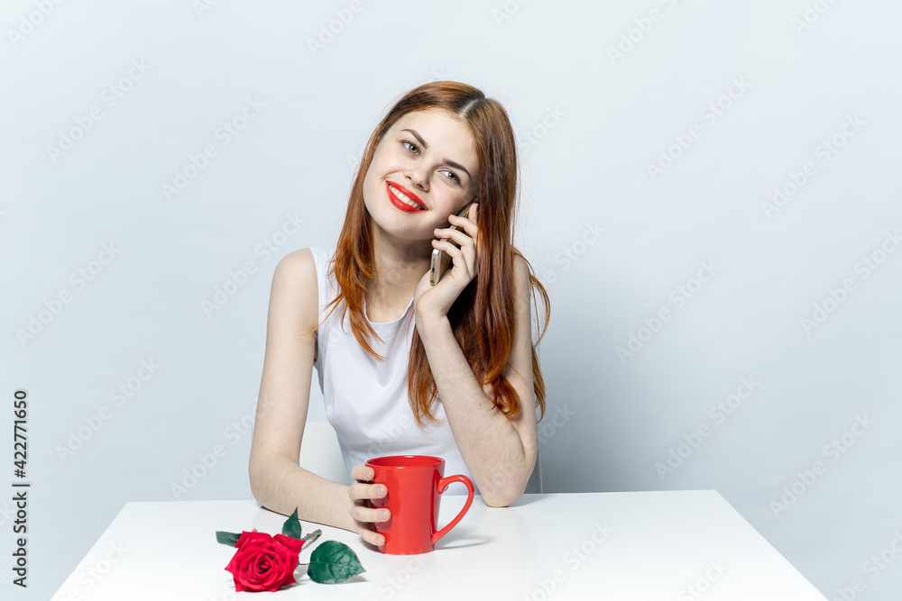 woman talking on the phone sitting at the table cup with a drink red rose woman talking on the phone sitting at the table cup with a drink red rose