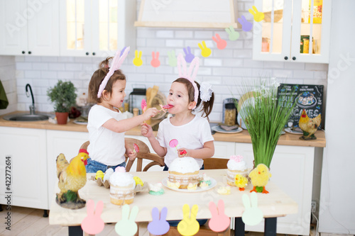 Two girls are trying Easter candies in the kitchen. Easter. Easter preparations
