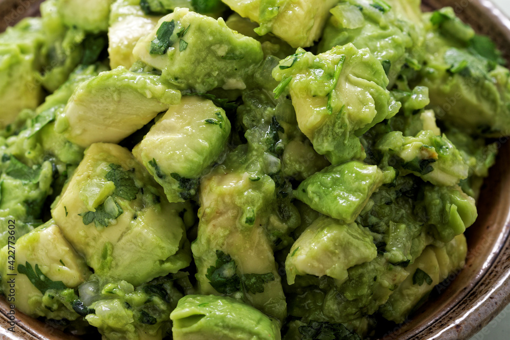 Close-up view of chunky guacamole in ceramic bowl. Mexican cuisine. Close-up view of chunky guacamole in ceramic bowl. Mexican cuisine.