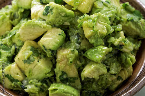 Close-up view of chunky guacamole in ceramic bowl. Mexican cuisine.