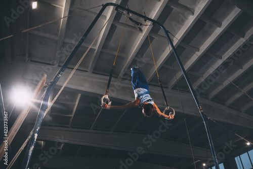 Little male gymnast training in gym, flexible and active. Caucasian fit little boy, athlete in sportswear practicing in exercises for strength, balance.