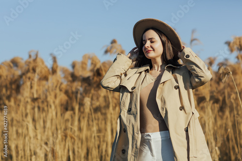 Tender girl with closed eyes with dry reed and blue sky on the background.