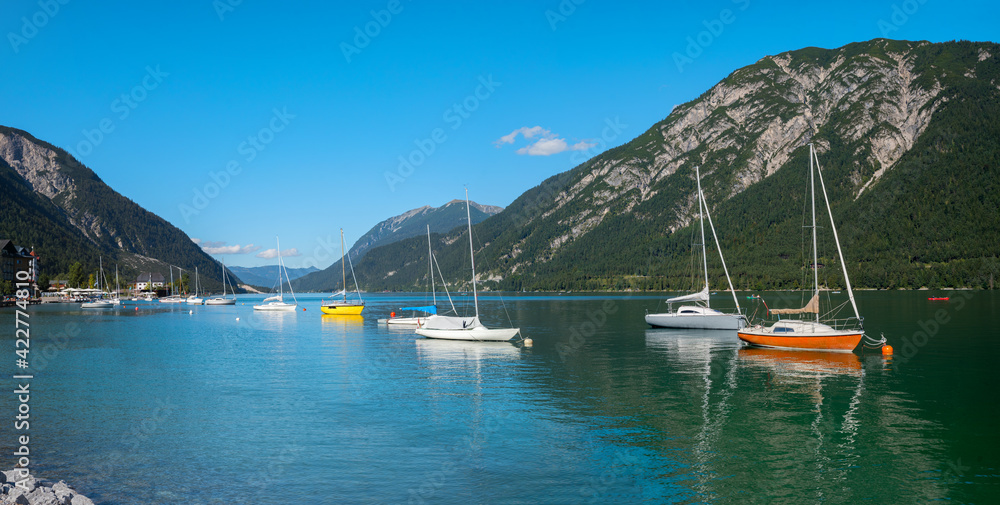 idyllic blue lake Achensee with moored sailboats, tourist resort austria