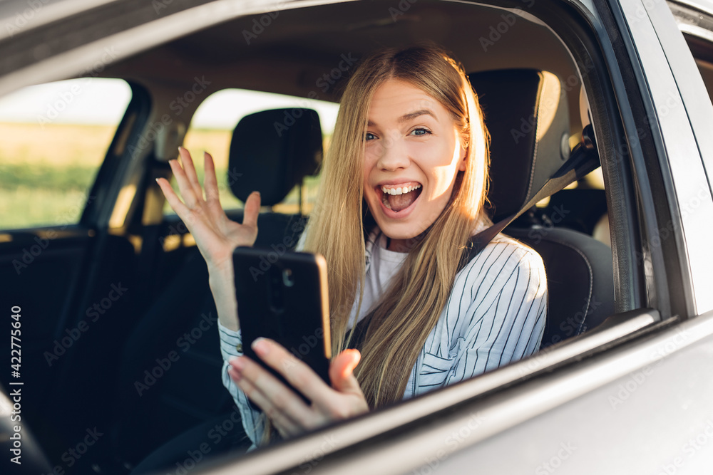 Young woman driving a car, using a mobile phone while traveling Young woman driving a car, using a mobile phone while traveling