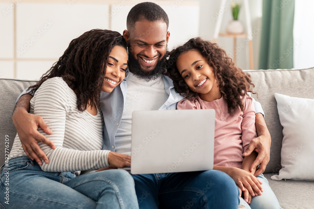 Happy African American family using laptop sitting on the couch Happy African American family using laptop sitting on the couch