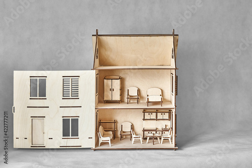 Cute doll house with toy furniture made of plywood details cut with laser machine tool stands with open wall on light grey