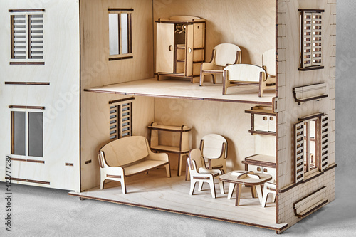 Cute doll house with toy furniture made of plywood details cut with laser machine tool stands with open wall on light grey closeup