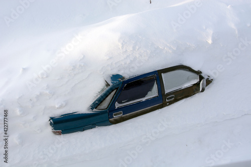 Car in a snowdrift, top view. The passenger car was covered with snow. There is a lot of snow outside.