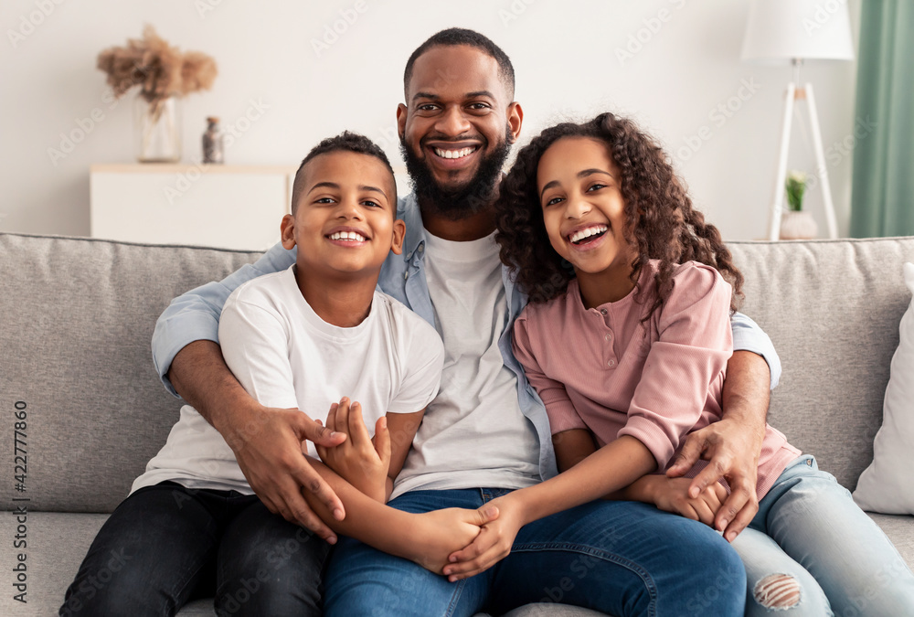 African american father hugging his children sitting on couch African american father hugging his children sitting on couch