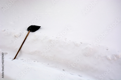 Snow shovel. A snow shovel lies on a snowdrift near the house.