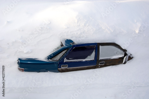 The car stands in the snow, top view. The passenger car was covered with snow. A car in a snowdrift.