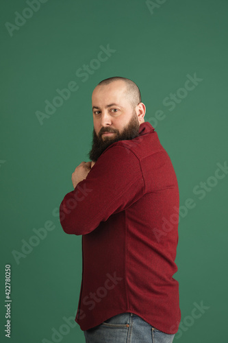 Handsome caucasian man portrait isolated on green studio background with copyspace