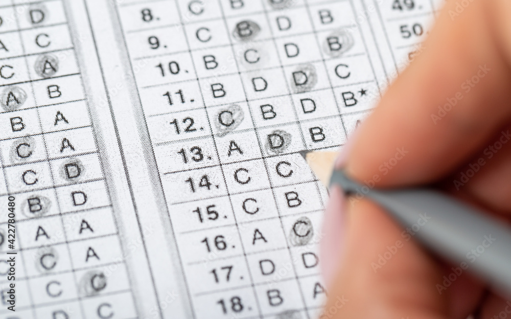 The student fills in the answers to the test in the exercise and examination paper with a pencil. education concept. The student fills in the answers to the test in the exercise and examination paper with a pencil. education concept.